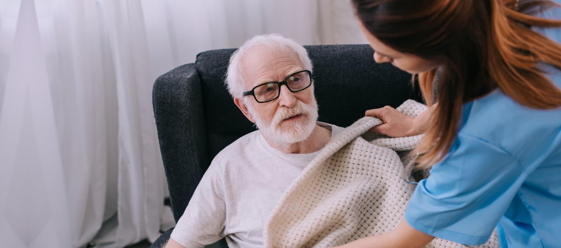 caregiver putting blanket to senior