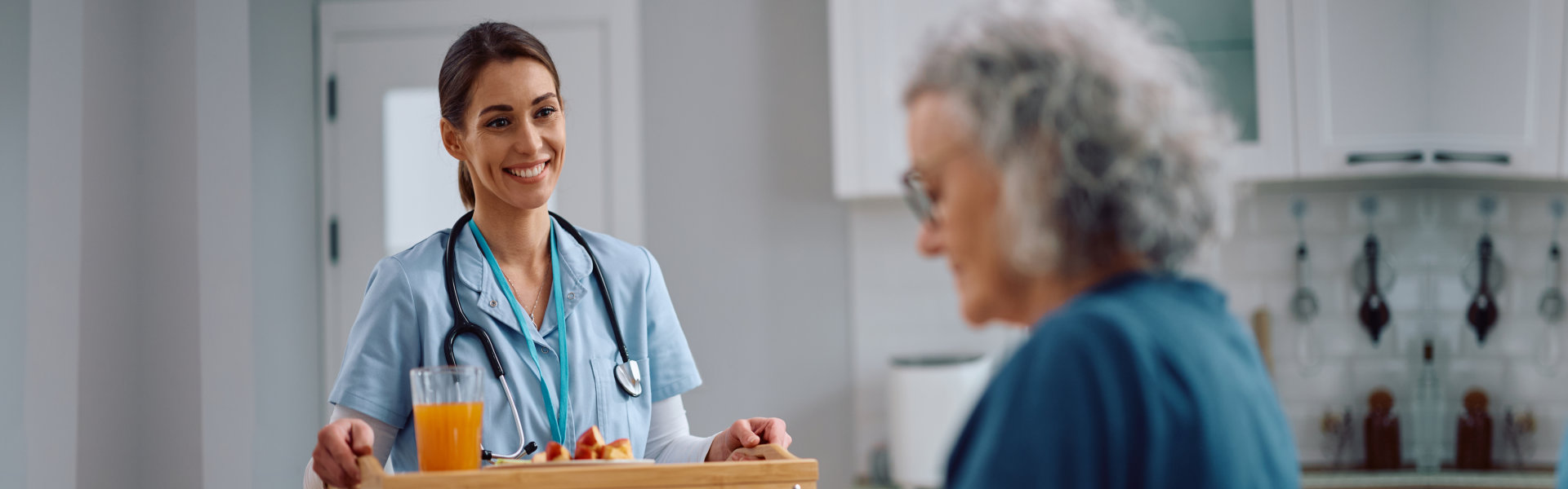nurse serving food to her senior patient during home visit.